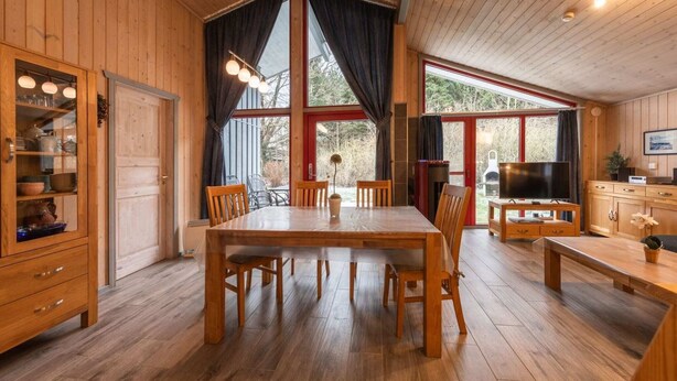 Un interior de madera con una mesa de comedor, sillas, un televisor y una zona de cocina.