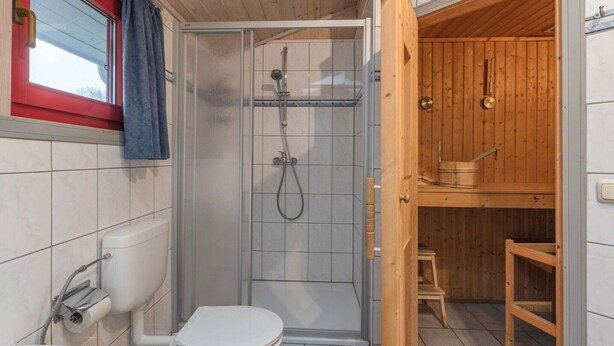 Een moderne badkamer met douche, toilet en wastafel.