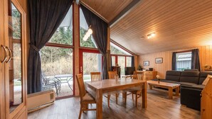 Un interior de cabaña acogedor con una mesa de comedor de madera, un sofá y un televisor.