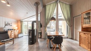 A cozy cabin interior with a dining area, kitchen, and a large window with curtains. - Ferienhaus mit Sauna im Ferienpark Mirow (Granzow)