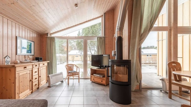 Un intérieur de chalet chaleureux, avec un revêtement en bois, un téléviseur, une cheminée et un coin repas.