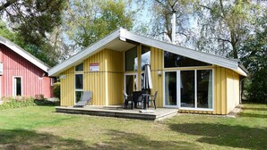 Un bâtiment jaune avec un patio couvert et, au fond, un bâtiment rouge.