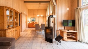 A wooden interior with a fireplace, a dining area, and a TV. - Ferienhaus mit Sauna im Ferienpark Mirow (Granzow)