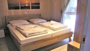 Ein Bett mit Holz-Kopfteil, ein Nachttisch und ein Fenster mit Vorhängen.