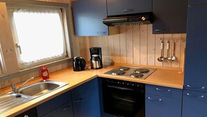 Eine kleine Küche mit Herd, Spüle und Kaffeemaschine.