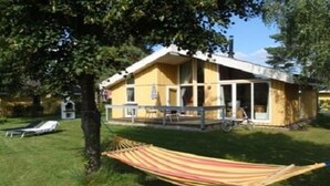 Une maison jaune avec un porche, un hamac et un vélo.
