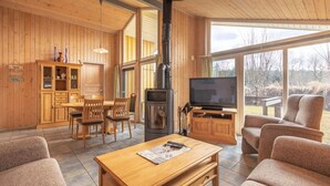 Un intérieur en bois comprenant un coin repas, un téléviseur et une cheminée.