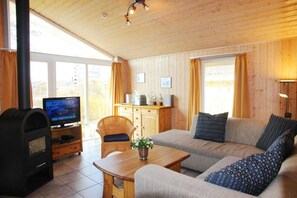 A cozy living room with a fireplace, sofa, television, and wooden cabinets.