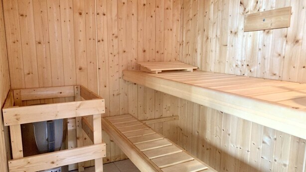 Eine Holzsauna mit Sitzbank und Ablagefläche.