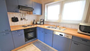 Eine moderne Küche mit blauen Schränken, einem Herd, einem Backofen, einer Spüle und einer Mikrowelle.