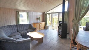 Ein geräumiges Wohnzimmer mit einer Couch, einem Couchtisch, einem Holzschrank und einem Grill.