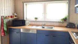 Eine kleine Küche mit Mikrowelle, Toaster, Spüle und einem Fenster mit Pflanzen.