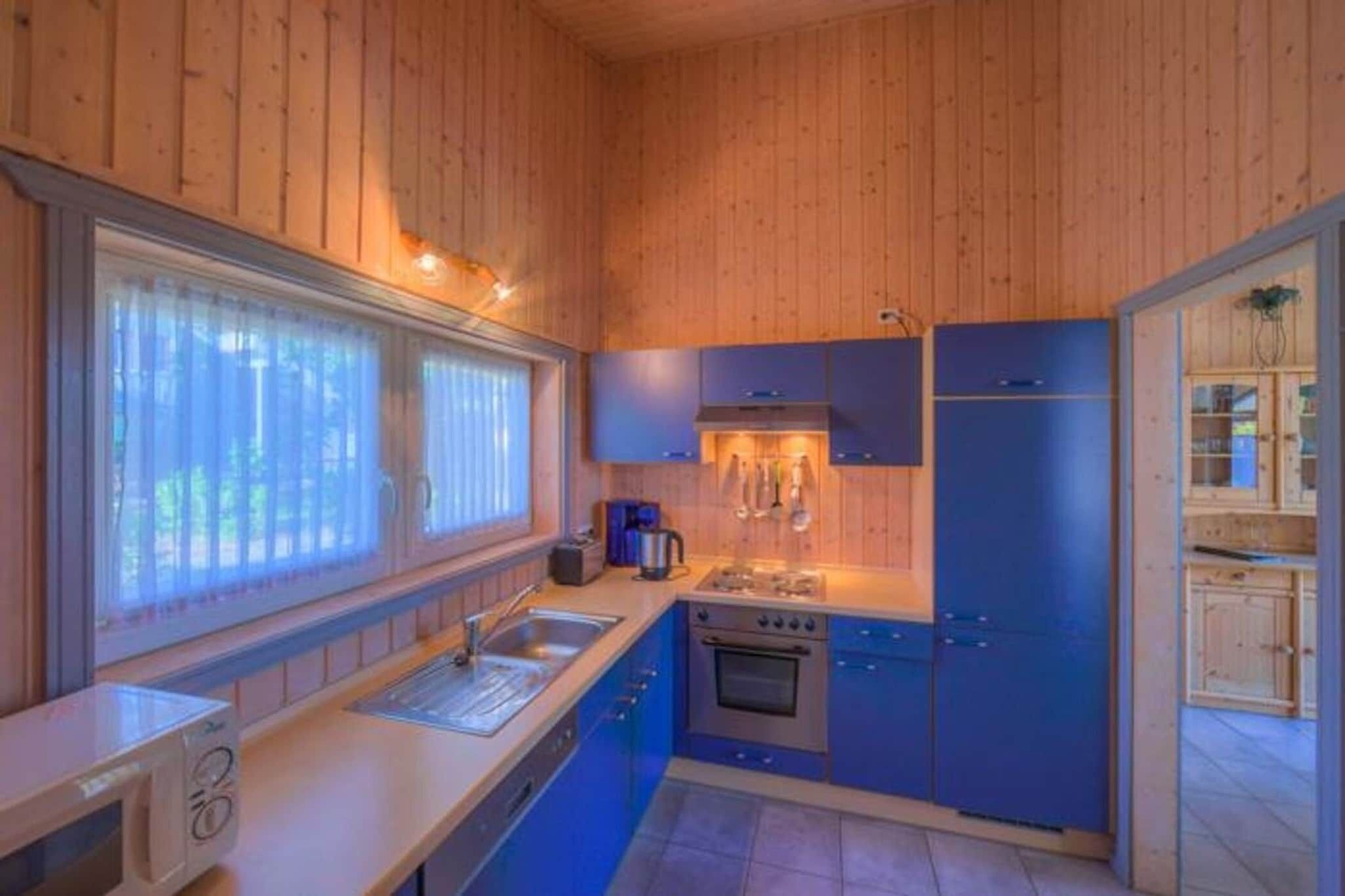 Une cuisine de taille réduite avec des murs en bois, un évier, une cuisinière et des placards.