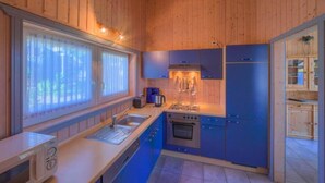 A compact kitchen with wooden walls, a sink, a stove, and cabinets. - Ferienhaus mit Sauna im Ferienpark Mirow (Granzow)