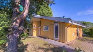 A small, single-story building with a yellow exterior, a door, and a window. - Ferienhaus mit Sauna im Ferienpark Mirow (Granzow)
