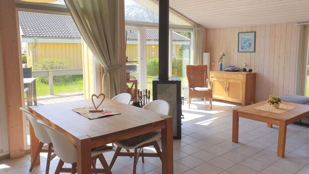 A spacious room with a wooden table and chairs, a sofa, a cabinet, and a fireplace. - Ferienhaus mit Sauna im Ferienpark Mirow (Granzow)