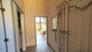 A hallway with wooden walls and a tiled floor, leading to a dining area with a table and chairs. - Ferienhaus mit Sauna im Ferienpark Mirow (Granzow)