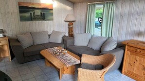 Ein gemütliches Wohnzimmer mit zwei Sofas, einem Holztisch, einem Korbstuhl und einem Schrank.