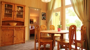 Ein Esszimmer mit Holzboden, einem runden Tisch, sechs Stühlen und einer Vitrine mit Glastüren.