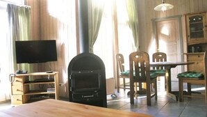 Una habitación con cama, televisor, chimenea, mesa de comedor con sillas y un armario.