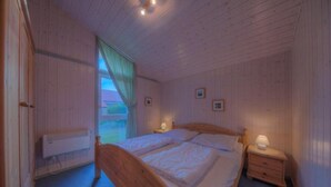 Une chambre à coucher avec un lit en bois, des tables de chevet avec des lampes et une fenêtre avec des rideaux.