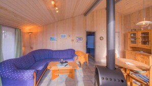 A cozy wooden cabin interior with a sofa, table, and a wood stove. - Ferienhaus mit Sauna im Ferienpark Mirow (Granzow)