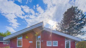 A red building with a sloped roof, a visible door, and a sign indicating a parking area. - Ferienhaus mit Sauna im Ferienpark Mirow (Granzow)