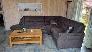 A modern living room with a large sectional sofa, a wooden coffee table, and a framed picture on the wall.