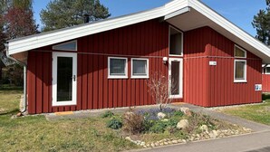 A red building with a sloped roof, a front door, and a small porch area.