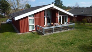 A red wooden house with a sloped roof and a covered porch.