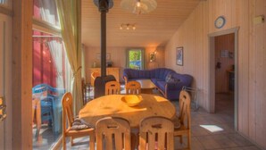 A wooden interior with a dining table, chairs, a sofa, and a ceiling fan. - Ferienhaus mit Sauna im Ferienpark Mirow (Granzow)
