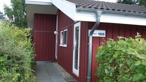 Ein rotes Gebäude mit einer Beschilderung mit der Nummer 166, einer Tür und einem kleinen Weg, der davorhin führt.