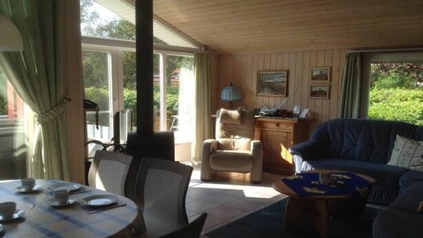 Ein Zimmer mit Esstisch für vier Personen, einer Couch, einem Sessel und einem kleinen Tisch mit einem Gesellschaftsspiel.