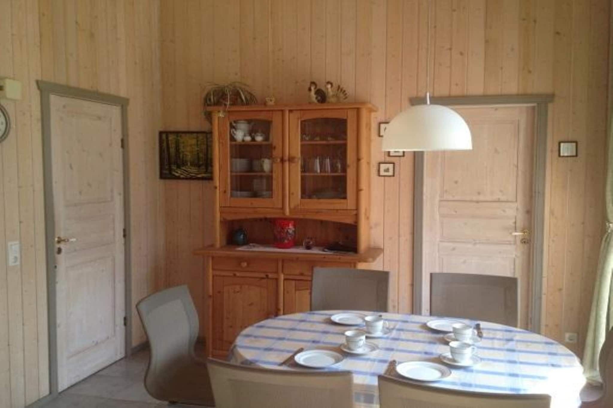 Un coin repas avec une table ronde pour quatre personnes, des meubles en bois et un luminaire suspendu.