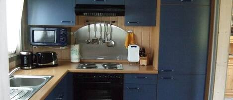 Una cocina compacta con microondas, estufa, pileta y alacenas.