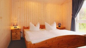 Un dormitorio con paneles de madera, una cama individual, dos lámparas de noche y una ventana con cortinas.