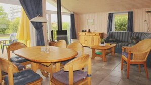 Una habitación acogedora con una mesa y sillas de madera, un sofá y un armario.