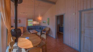 Ein gemütliches Zimmer mit einem Holzesstisch, Stühlen, einem Sofa und einem großen Fenster.