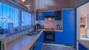 A modern kitchen with blue cabinets, a stove, and a sink.
