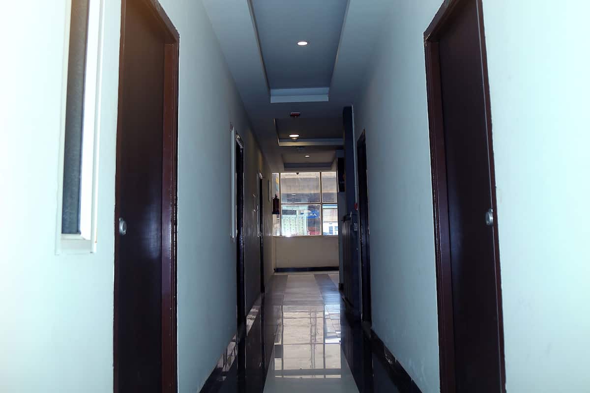 A long, narrow hallway with dark wooden doors on either side and a tiled floor.