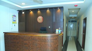A reception desk with a clock, a calendar, and a hand sanitizer dispenser. - MR DWELL HOTEL AIRPORTZONE (Hyderabad)