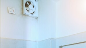 A bathroom with a white toilet, a shower area, and a handrail. - MR DWELL HOTEL AIRPORTZONE (Hyderabad)