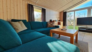 Een gezellige woonkamer met een blauwgroene bank, een houten salontafel en een flatscreen televisie.