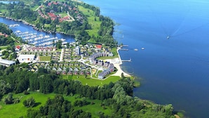 Vue aérienne d’un quartier résidentiel au bord d’un lac, avec un port de plaisance, des maisons et un petit quai.