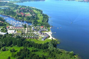 An aerial view of a lakeside residential area with a marina, houses, and a small dock.