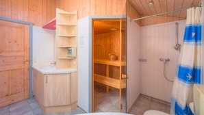 Une salle de bain rustique, aménagée dans une cabane en bois, avec une douche, des toilettes et un lavabo.
