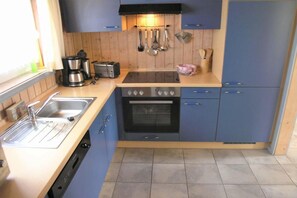 A compact kitchen with a sink, stove, and oven. There are cabinets and a countertop.