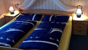 Ein Schlafzimmer einer Holzhütte mit einem Bett, zwei Nachttischlampen und einem Baldachin.