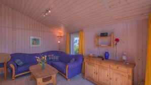 Et hyggeligt værelse med en blå sofa, et træskab og et lille bord med en vase.