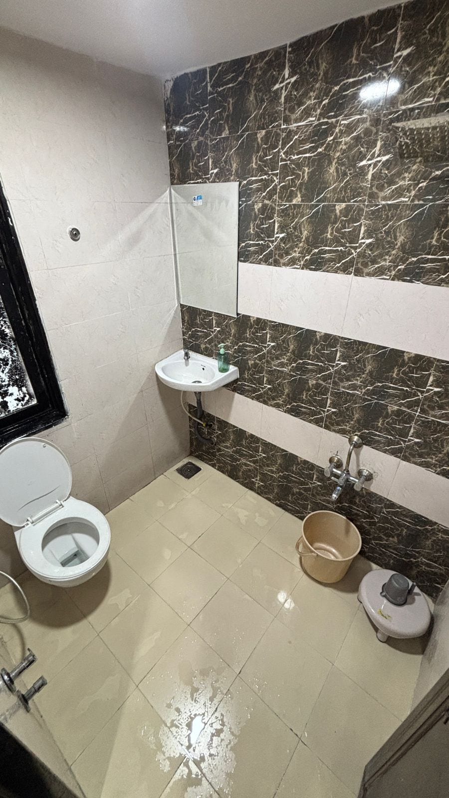 A bathroom with a toilet, sink, and mirror.